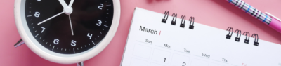 A clock, calendar and pen on a pink background